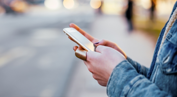 Woman looking at her phone while standing on the sidewalk
